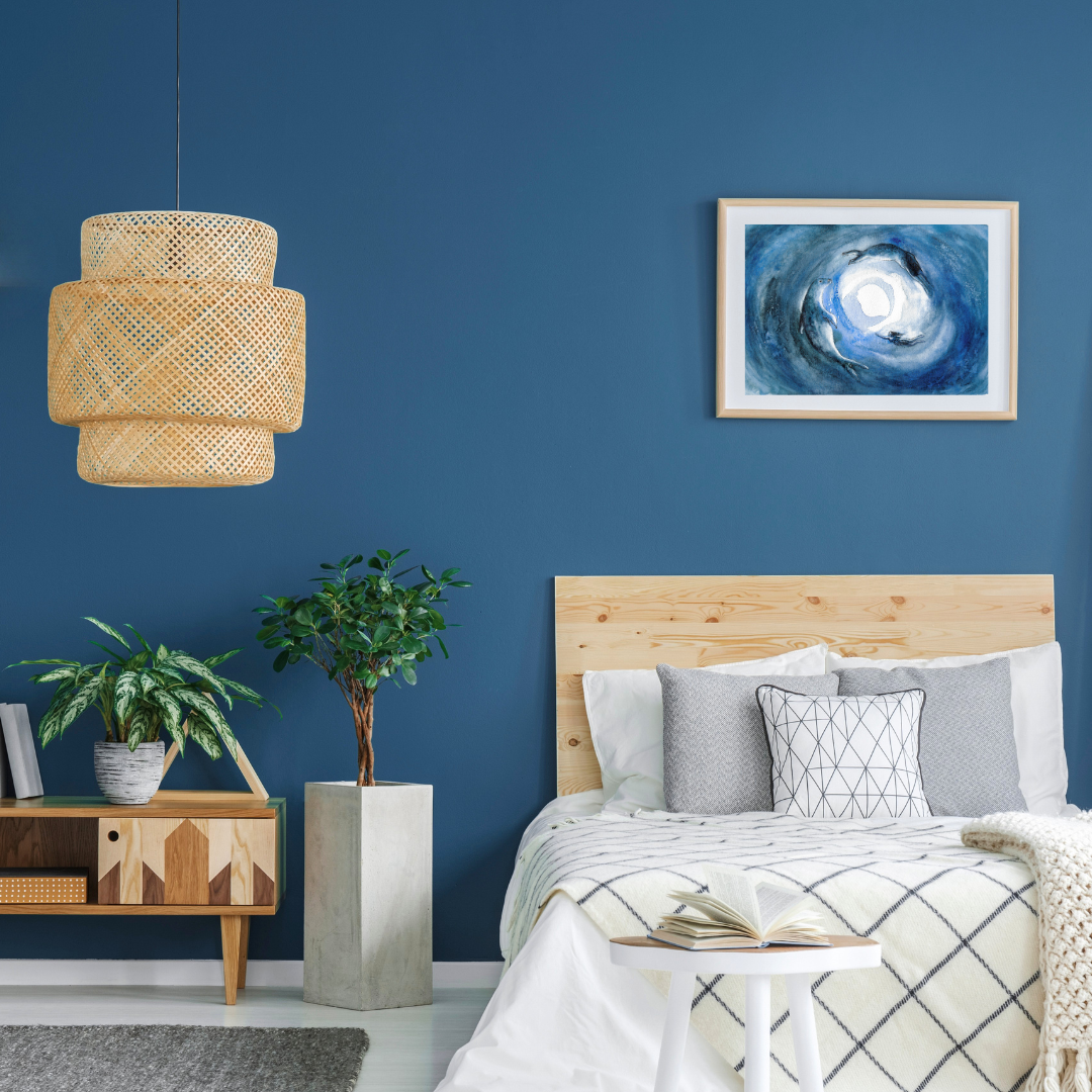 Modern bedroom with blue walls, wooden headboard, and a watercolour print of a seal, a selkie and the full moon.